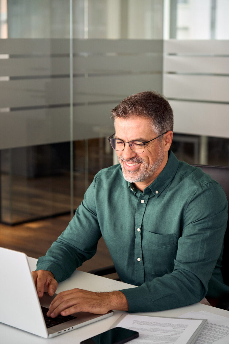 smiling busy mature professional business man working on laptop in office.